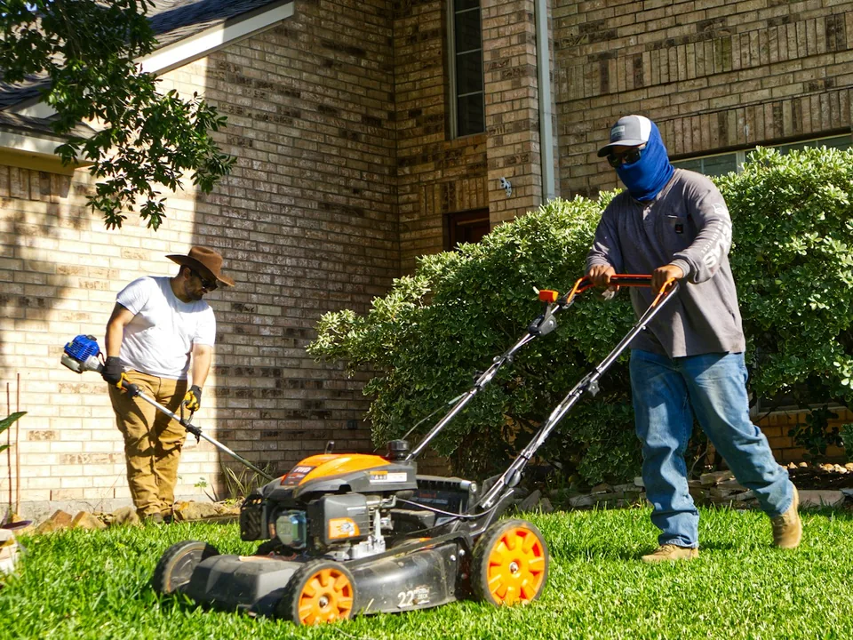 Two-person lawn crew mowing and trimming a front yard