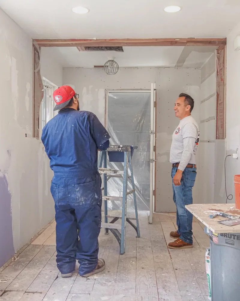Frank Alcaraz, smiling, with an FAC Construction crew member on a remodel job site